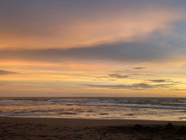 Gün batımında kumlu bir sahilin dikey görüntüsü.