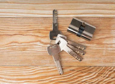 Kapı kilidi için anahtarlar ve kilit silindiri. Pin takla bileşenleri yenilenmeye ya da onarılmaya hazır, ahşap arka plandaki herhangi bir evin güvenliği kapatılmaya hazır