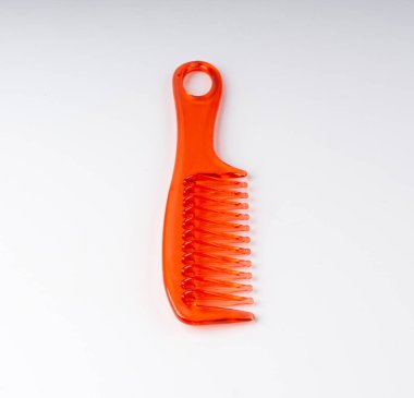 Turuncu plastik tarak izole edildi. Yeni renk saç fırçası, renkli berber aracı, beyaz arkaplanda büyük kırmızı tarak