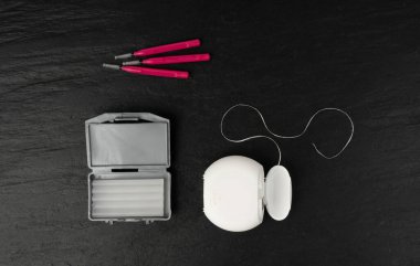 Diş ipi, ortodontik balmumu kutusu ve diş fırçaları. Diş sağlığı seti, siyah arka planda diş bakımı koleksiyonu.