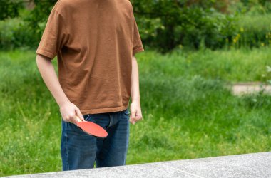 Parkta masa tenisi. Ping pong yaz sporu dışarıda, ergen masa tenisi oynuyor seçici odaklı, bulanık arka planlı