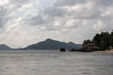 Beautiful evening view from Anse Source d Argent beach with granite boulders clear water and forested coastline on La Digue Island Seychelles