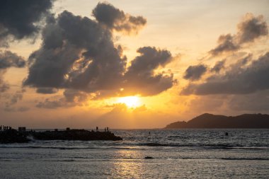 La Digue 'den gün batımı manzarası Praslin Adası' nın silueti ve sakin denizde altın yansıması