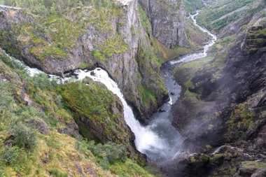 Voringfossen şelalesi Eidfjord, Norveç 'te, Hardangervidda platosundan derin bir kanyona dökülüyor. Uçurumları ve nehir akışı olan manzaralı dağ manzarası