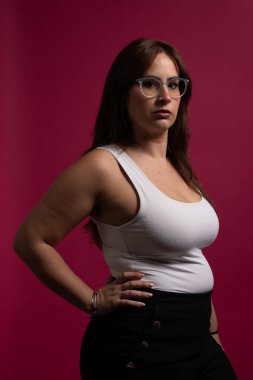 Pembe arka planda gözlük takan kendine güvenen gerçek bir kadın.