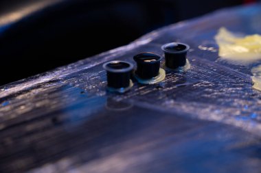 Plastik film ile kaplı çalışma alanında üç küçük siyah mürekkep bardağı.