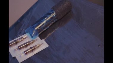 Profesyonel dövme sanatçısı steril bir çalışma istasyonunda aletler, mürekkep ve ekipman hazırlıyor.