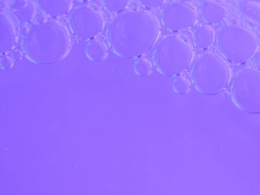 Camsı kabarcıklar canlı mor sularda usulca süzülür.