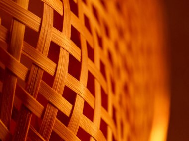 Hasır sepetin yakın çekim makrosu karmaşık bir bambu dokuma deseni ve sıcak kehribar aydınlatma, doğal dokuyu, işçiliği ve arka plan veya dekoratif kullanım için tekrarlanan geometrik çizgileri gösterir.