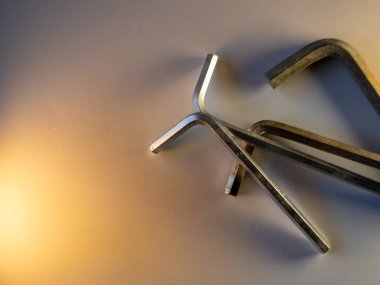 Metal uğursuz tuşlar pürüzsüz bir yüzeye saçılmış. Yumuşak ışık, sahnenin her yerinde ılık tonlar oluşturur. Aletler hassasiyet ve kullanımla parıldıyor. Minimalist kompozisyon temiz çizgiler ve dokuları vurguluyor