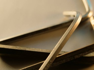 Metal çubuk sıcak ışık altında hafifçe parıldar. Eğri kenar ince altın parıltıyı yansıtır. Yığılmış parçalar pürüzsüz ve titiz işçilik gösteriyor. Endüstriyel dokular güç ve dayanıklılığı gösteriyor