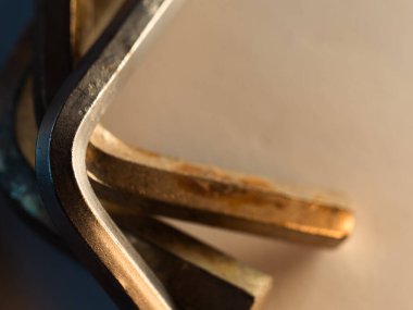 Endüstriyel hassasiyetle parıldayan altın bir alet. Pürüzsüz kıvrımlar, metalik ahenkte keskin kenarlarla kesişir. Sıcak ışık cilalanmış yüzeyi ve ince aşınmayı vurgular