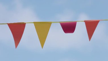 Rengarenk üçgen bayrakların büyüleyici güzelliğini hisset narin meltemde dalgalanıp el değmemiş mavi gökyüzüne karşı, neşe ve sevinç hisleri uyandıran.