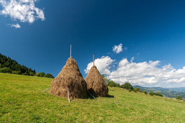 Two haystacks in the mountains. Beautiful Carpathian landscape.