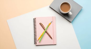 Üzerinde çapraz kalemler, bir fincan kahve ve pastel renkli bir yüzey üzerine boş bir kağıt olan pembe bir defter resmi. Yaratıcı işler ve kavramlar için ideal..