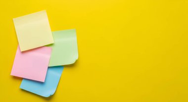 Parlak sarı bir zemin üzerine yerleştirilmiş pastel renkli yapışkan notlar yığını hatırlatıcılar, notlar veya örgütsel amaçlar için mükemmeldir..