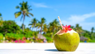 Tropik plajda çiçek ve samanla taze hindistan cevizi içeceği, güneş