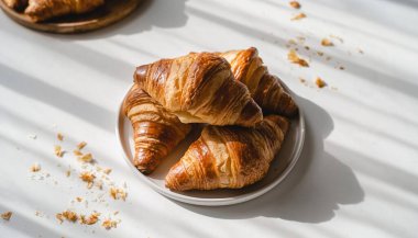 Güneş ışığıyla aydınlatılmış taze kruvasanların yakın plan çekimi kahvaltı ya da kahvaltı için mükemmel ve davetkar bir sahne yaratır..