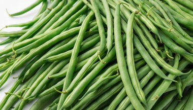 Canlı yeşil fasulye yığını, doğal renklerini ve dokusunu sergiliyor, sağlıklı yemek ve yemek pişirme için mükemmel..