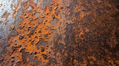 Detaylı bir yakın plan, paslanmış, pul pul boyanmış bir metal yüzeyin dokusunu ve renk değişimlerini ortaya çıkararak aşınmanın etkilerini gözler önüne seriyor..