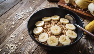 Muz dilimleri sıcak dökme demir bir tavanın içinde sade ahşap bir masada çekilmiş.