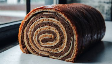 Kremalı dolgu ve kıvrımlı kıvrımları ortaya çıkarmak için dilimlenmiş İsviçre usulü çikolatalı bir pasta..