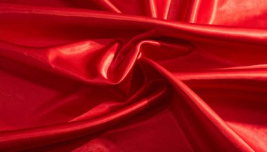 Katları ve yansımaları olan ipeksi kırmızı saten kumaşı kapat ve arka plan ve tasarım projeleri için uygun zengin bir tekstil dokusu oluştur.