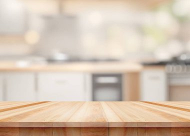 Arka planda bulanık aletler ve dolaplarla dolu modern bir mutfakta temiz ahşap bir masa.