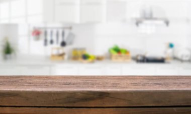 Arka planda bulanık sebzeler ve çatal bıçaklarla dolu sıcak bir ahşap tezgah.