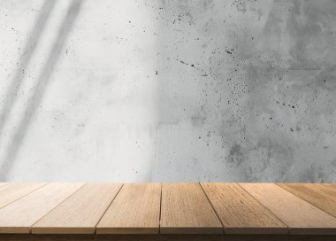 Basit bir ahşap masa, beton bir duvarın önünde oturur ve temiz bir minimalist stüdyo estetiği yaratır.