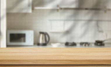 Ahşap tezgah, mikrodalga fırın, elektrikli su ısıtıcısı ve gaz sobasının yumuşak, bulanık fayanslı bir duvara dayandığı modern bir mutfak sahnesi..