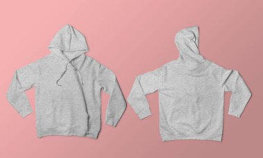 İki açık gri kapüşonlu sweatshirt moda ve giysi modelleri için yumuşak pembe bir zemin üzerine serilmişti.