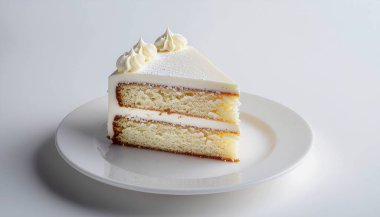 Kremalı kremalı tek bir vanilyalı pasta dilimi beyaz bir tabakta duruyor..