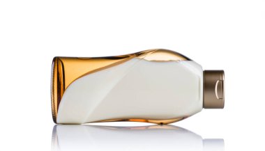 Parlak bir kehribar şişesi beyaz bir zemin üzerinde duruyor, kavisli cam ve metalik kapağını sergiliyor.