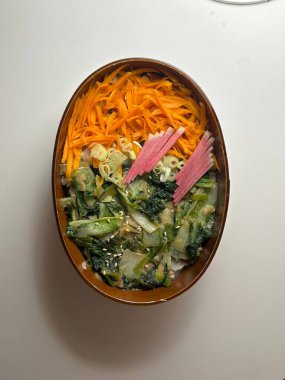 Geleneksel bir Kore dozirak 'ı. Pirinç, çeşitli banchan ve tuzlu proteinlerle güzelce düzenlenmiş. Dengeli ve görsel olarak davetkâr, canlı lezzetlerle dolu taşınabilir bir yemek..