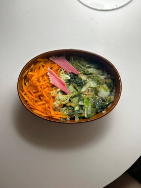 Geleneksel bir Kore dozirak 'ı. Pirinç, çeşitli banchan ve tuzlu proteinlerle güzelce düzenlenmiş. Dengeli ve görsel olarak davetkâr, canlı lezzetlerle dolu taşınabilir bir yemek..