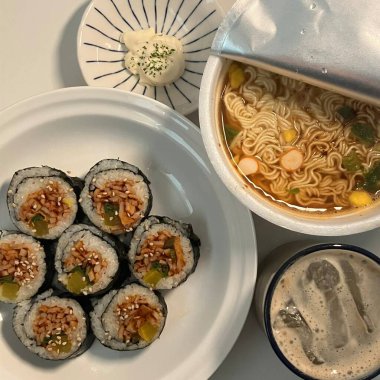 Kimbap ve Ramyun, mükemmel bir Kore karışımı! Lezzetli pirinç rulolarının yanında sebze, et ve turşu ile baharatlı ve rahatlatıcı ramen ye. Günün her saatinde doyurucu bir yemek..