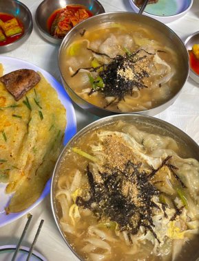 Warm bowl of Mandu-guk, a traditional Korean soup with soft dumplings, sliced rice cakes, and green onions in a savory broth. Comforting and flavorful, perfect for a hearty meal.