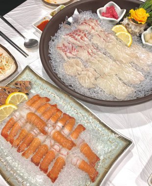 Taze ve narin sashimi dilimleri, canlı renkler ve mükemmel kesimlerle güzelce sunuluyor. Bu geleneksel Japon lezzeti kaliteli deniz ürünlerinin saf tatlarını vurgular..