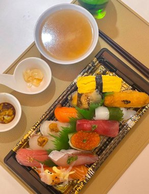 Çeşitli malzemeler ve canlı renklerle sanatsal olarak düzenlenmiş taze suşi çeşitleri. Bu geleneksel Japon yemeği bir deneyim için sirkeli pirinç, deniz ürünleri ve sebzeleri birleştirir..