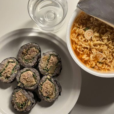 Kimbap ve Ramyun, mükemmel bir Kore karışımı! Lezzetli pirinç rulolarının yanında sebze, et ve turşu ile baharatlı ve rahatlatıcı ramen ye. Günün her saatinde doyurucu bir yemek..