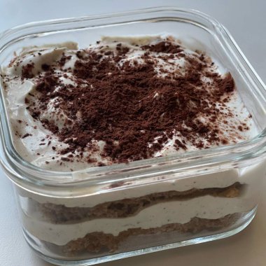Yumuşak ve kremalı tiramisu dilimi, zengin mascarpone, espressoya batırılmış kadın parmakları ve kakao tozu ile kaplı, her ısırıkta mükemmel bir tatlılık dengesi ve koyu kahve tadı sunuyor..