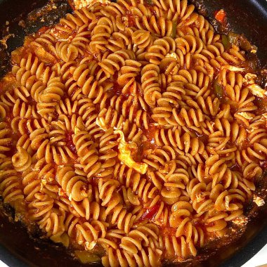 Freshly cooked pasta with smooth, tender strands glistening, lightly coated in sauce, showcasing its soft texture, warm steam, and inviting golden hue in close-up detail