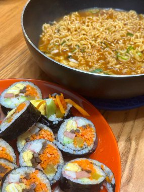 Kimbap ve Ramyun, mükemmel bir Kore karışımı! Lezzetli pirinç rulolarının yanında sebze, et ve turşu ile baharatlı ve rahatlatıcı ramen ye. Günün her saatinde doyurucu bir yemek..
