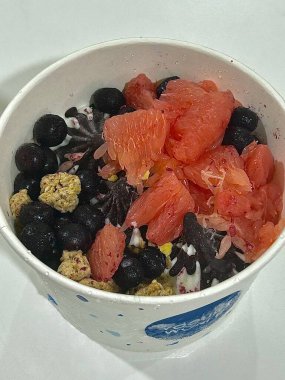 Doldurulmuş yoğurtlu tatlı bir fincanda servis ediliyor, pürüzsüz kremalı dokular, parlak yüzeyli, taze meyve parçaları ile kaplı, ferahlatıcı ve davetkar görünümünü detaylıca vurgulayan.