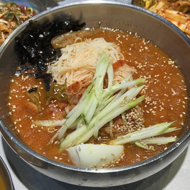 Chilled, chewy naengmyeon noodles in tangy broth paired with juicy, savory mandu dumplings, offering a perfect balance of refreshing coolness and hearty comfort in every delicious Korean bite.