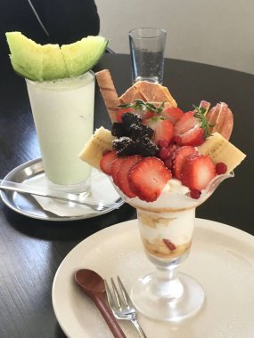 Taze meyveyle yapılmış çilekli parfe ve kırsal beyaz bir masanın üzerinde yoğurt. Bulanık arkaplan ve arkaplan ile seçmeli odak.