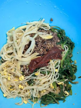 Bibimbap, çeşitli sebzeler, gochujang ve sıklıkla dilimlenmiş etin eşlik ettiği kızarmış yumurta ile süslenmiş canlı bir Kore pirinç yemeği. Karıştırıldığında, aromalı ve dengeli olur..