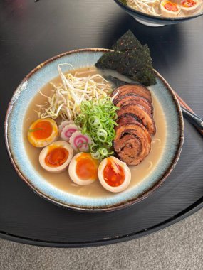 Buharlı bir kase çorba, taze erişte, dilimlenmiş domuz eti, haşlanmış yumurta, nori ve taze yeşil soğan. Rahatlatıcı ve lezzetli bir Japon klasiği..