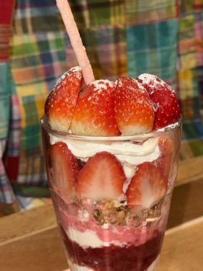 Taze meyveyle yapılmış çilekli parfe ve kırsal beyaz bir masanın üzerinde yoğurt. Bulanık arkaplan ve arkaplan ile seçmeli odak.